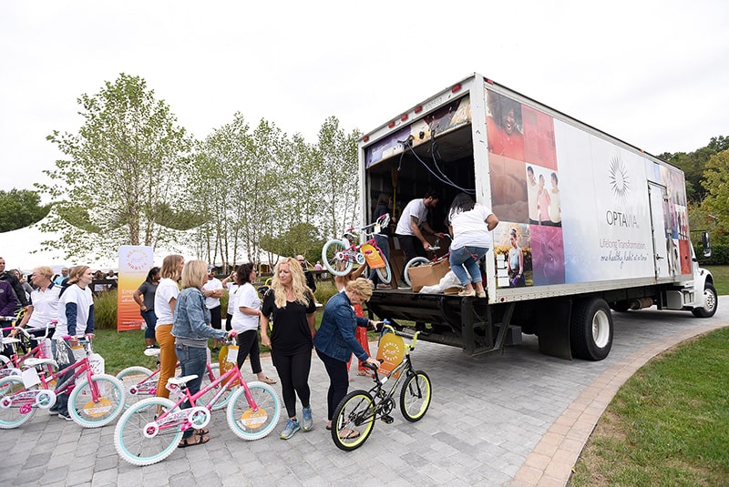 Volunteers loading bicycles for donation to school children into a large truck.