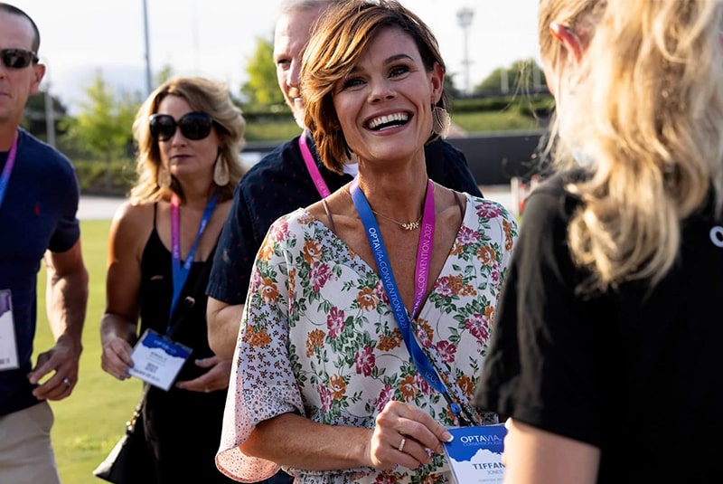 A female attendee smiles for the camera as she enters the Optavia block party.