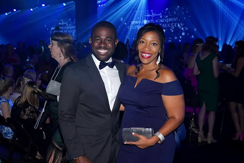 A male and female couple posing for the camera at the Celebration on Success Ceremony, in formal black tie attire, smiling.