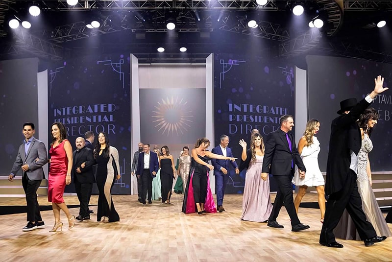 Optavia Coaches walking on stage during the Celebration on Success Ceremony, smiling and waving to the audience.
